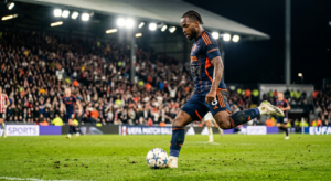 A cinematic close-up shot of a focused professional football player preparing to strike the ball dur