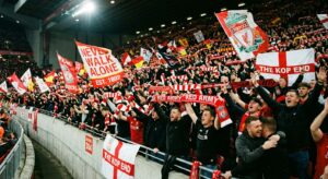 A cinematic, high-angle editorial photograph of a passionate crowd of football supporters in a stadi